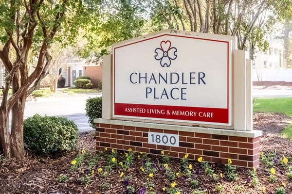 Sign for Chandler Place Assisted Living, surrounded by greenery