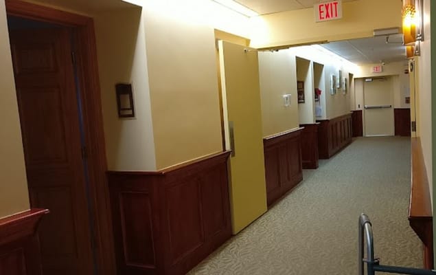 A well-lit hallway with wooden paneling and doors.