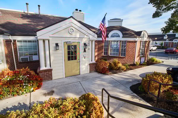 Exterior view of the facility entrance with flowers and flag