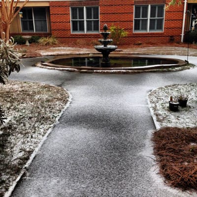 Snow-covered path leading to a fountain in a garden