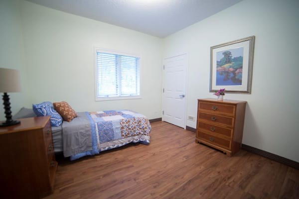 A cozy, private resident room with a bed and dresser