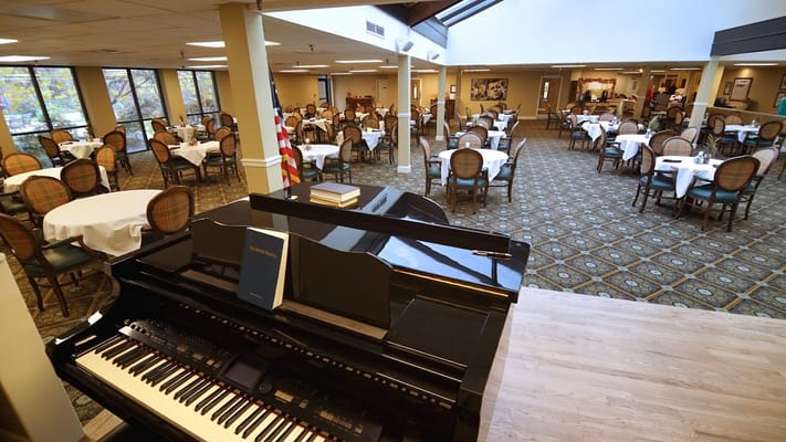 Interior view of a dining room with tables and a piano