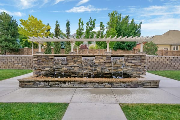 Stone waterfall feature with a pergola in the garden.