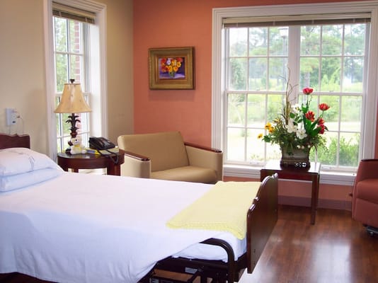 Patient bedroom featuring a bed, armchair, and a view out the window
