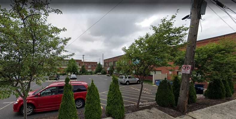 Outdoor view of parking area with trees and a building behind