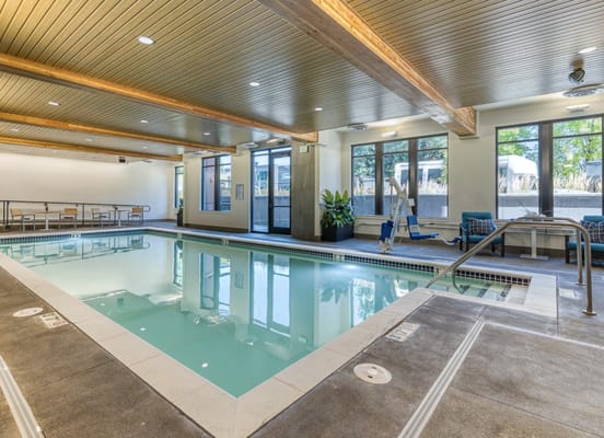 Indoor swimming pool area with seating and natural light