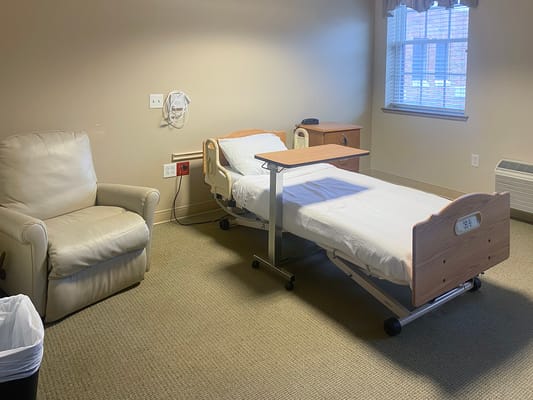 Private resident room with a hospital bed and armchair