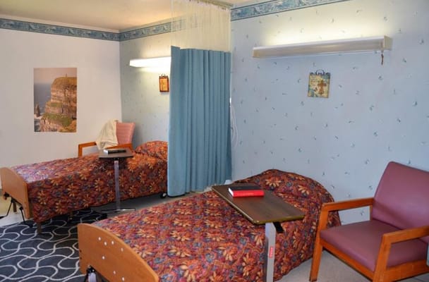 Private resident room with two beds and a chair