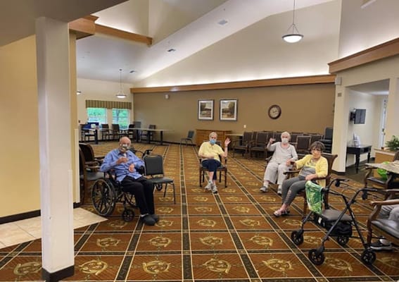 Group of residents in a lounge area with chairs and a large window