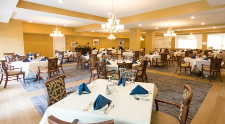 Spacious dining area set for meals with blue napkins and elegant lighting.
