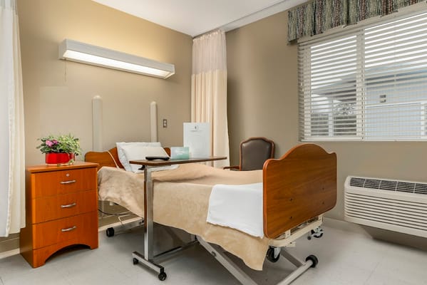 A well-furnished bedroom with a hospital bed and wooden nightstand.