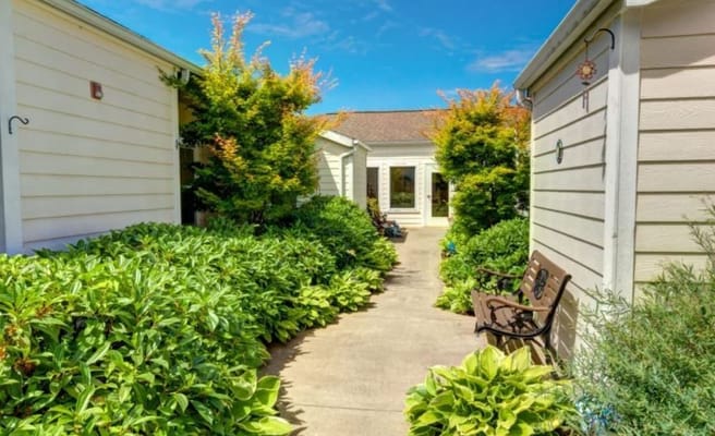 A landscaped pathway leading to the entrance of a memory care facility.