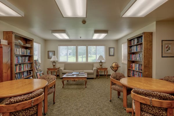 A well-lit library space with bookshelves, seating, and a coffee table.