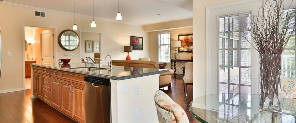 Open kitchen and living area with wooden cabinetry and dining table