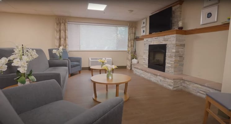 A cozy living room with two chairs, two tables, and a fireplace.