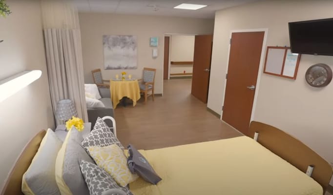 Interior view of a senior living room with a bed, seating area, and table.