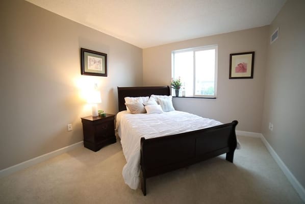 A well-decorated bedroom with a bed, nightstand, and window.