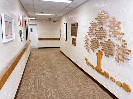 Long hallway featuring framed artwork and a memory tree installation.