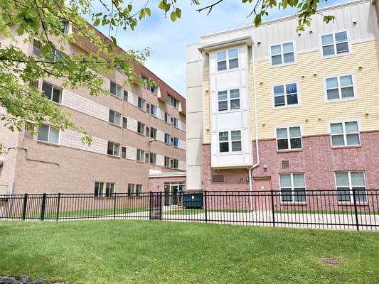 Exterior of University Gardens II building with green grass and fencing.
