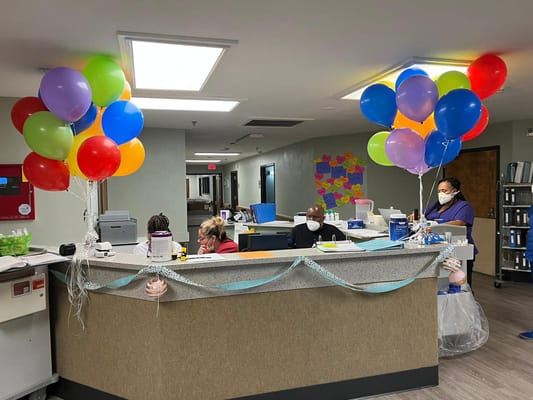 Colorful balloons at the reception desk with staff members at work.