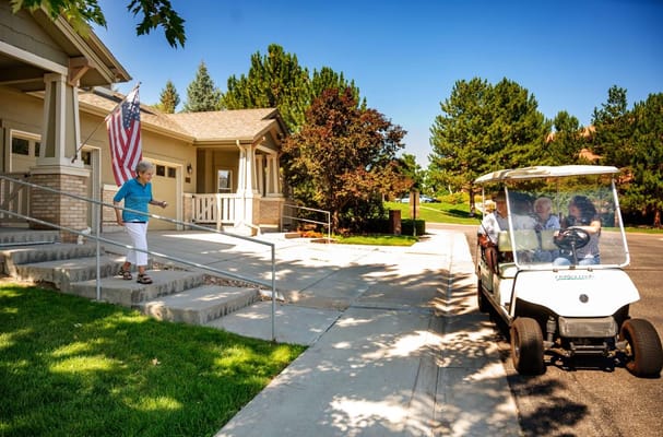 A resident walking down the steps towards a golf cart while holding an American flag.