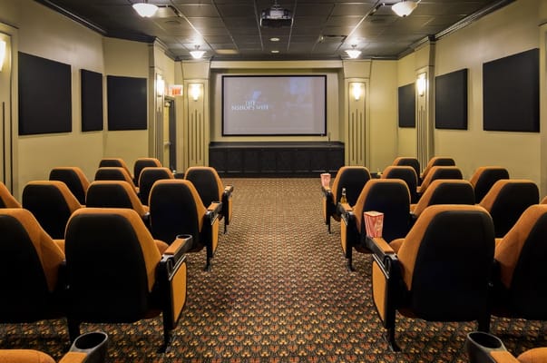 Interior of a theater room with orange seats and a movie screen