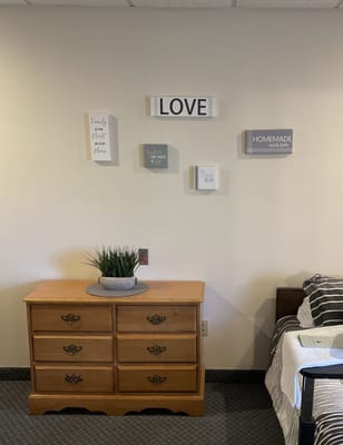 Cozy resident room with decorative wall art and dresser