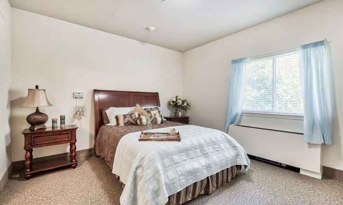 Neatly decorated bedroom with a bed, nightstand, and window