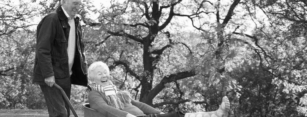 Couple enjoying a laugh in a garden wheelbarrow
