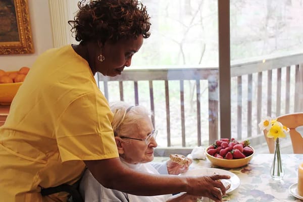 Caregiver assisting a resident with food at a table