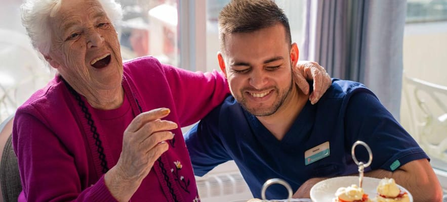 Resident enjoying tea with a staff member