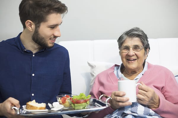 Caregiver serving food to a smiling resident