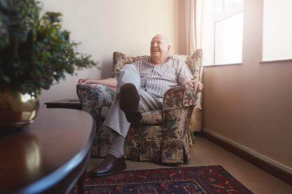 Resident relaxing in a cozy armchair in a facility room