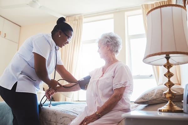 Nurse checking a resident's blood pressure in a room.