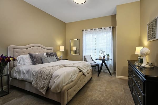 Well-decorated private resident room with a bed and seating area