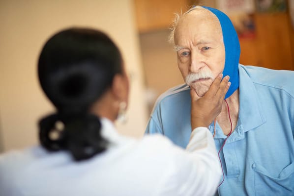 Healthcare professional assisting an elderly man in a care facility
