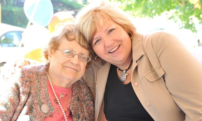 A resident and staff member smiling together outdoors
