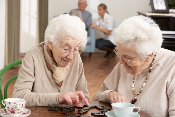 Two residents enjoying a game of dominoes at a table