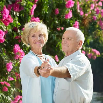 Elderly couple dancing in a garden with flowers