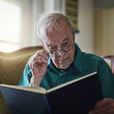 An elderly man reading a book indoors
