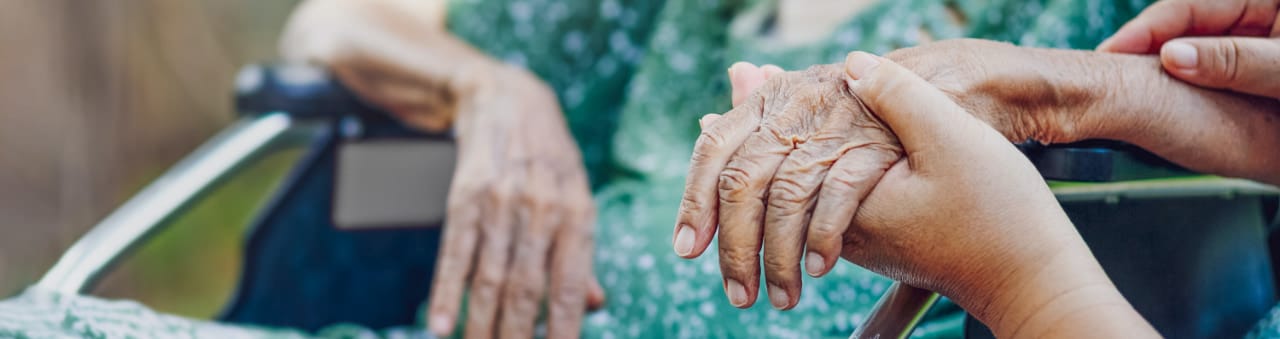 A caregiver holding the hand of a senior resident
