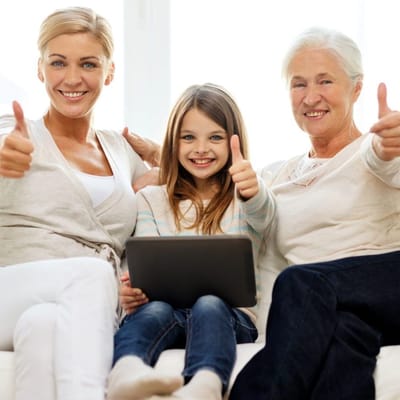 Three generations smiling and giving thumbs up in a cozy setting