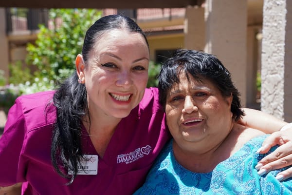 A staff member and a resident smiling together outdoors