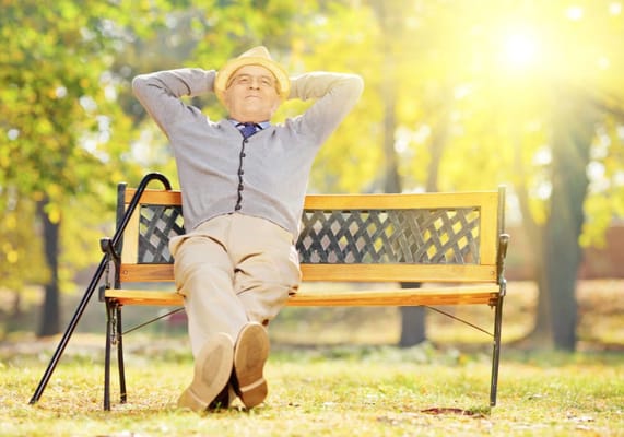 Senior man relaxing on a bench in a sunlit park
