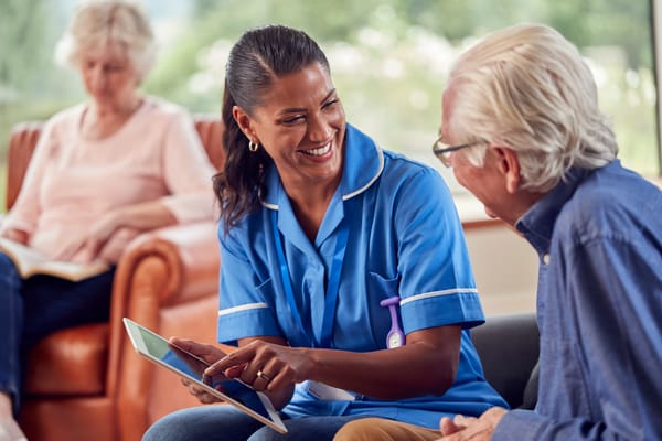 Caregiver assisting a senior resident with a tablet