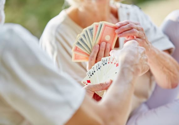 Residents playing cards outdoors in a sunny setting