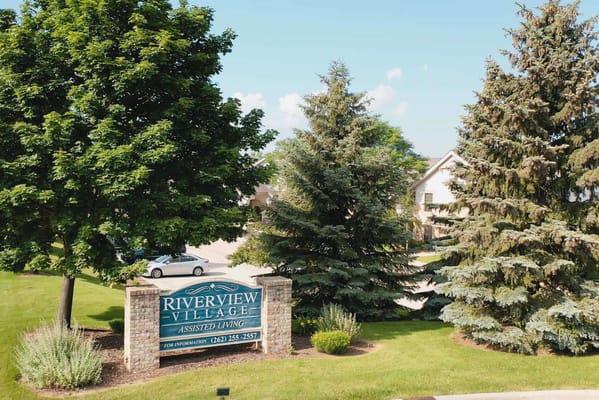 Sign for Riverview Village Assisted Living surrounded by trees