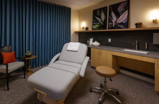 A treatment room with a massage table and artwork