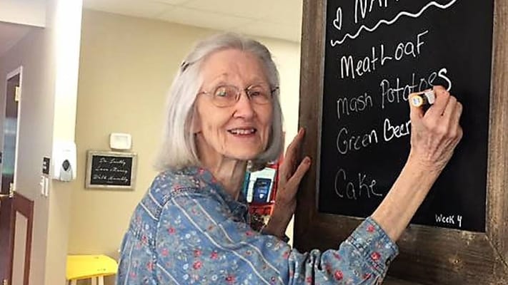 Resident writing the weekly menu on a chalkboard