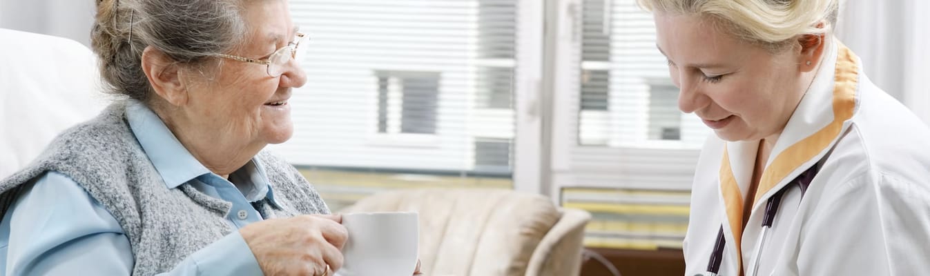 A caregiver smiling with a senior resident in a cozy room